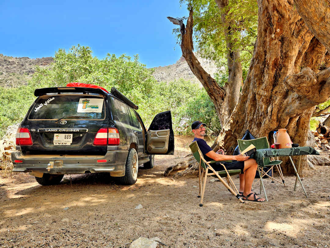 4wd at ayhaft canyon Man relaxing with book by SUV and tree