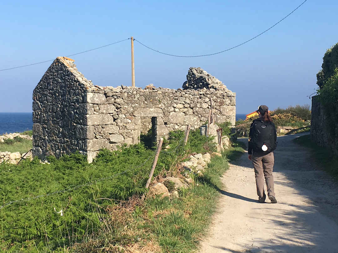 Camino de Santiago Sandra walking past house ruins Camino de Santiago Sandra walking past house ruins