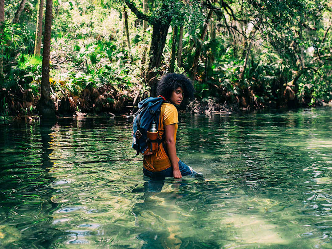 Person with backpack walking through a river by KAL VISUALS on Unsplash