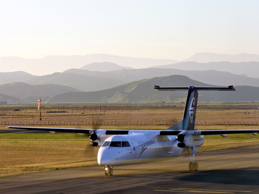 Turboprop airplane taxiing on runway at sunset