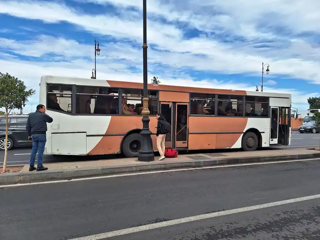 Passengers boarding a city bus on a sunny day.
