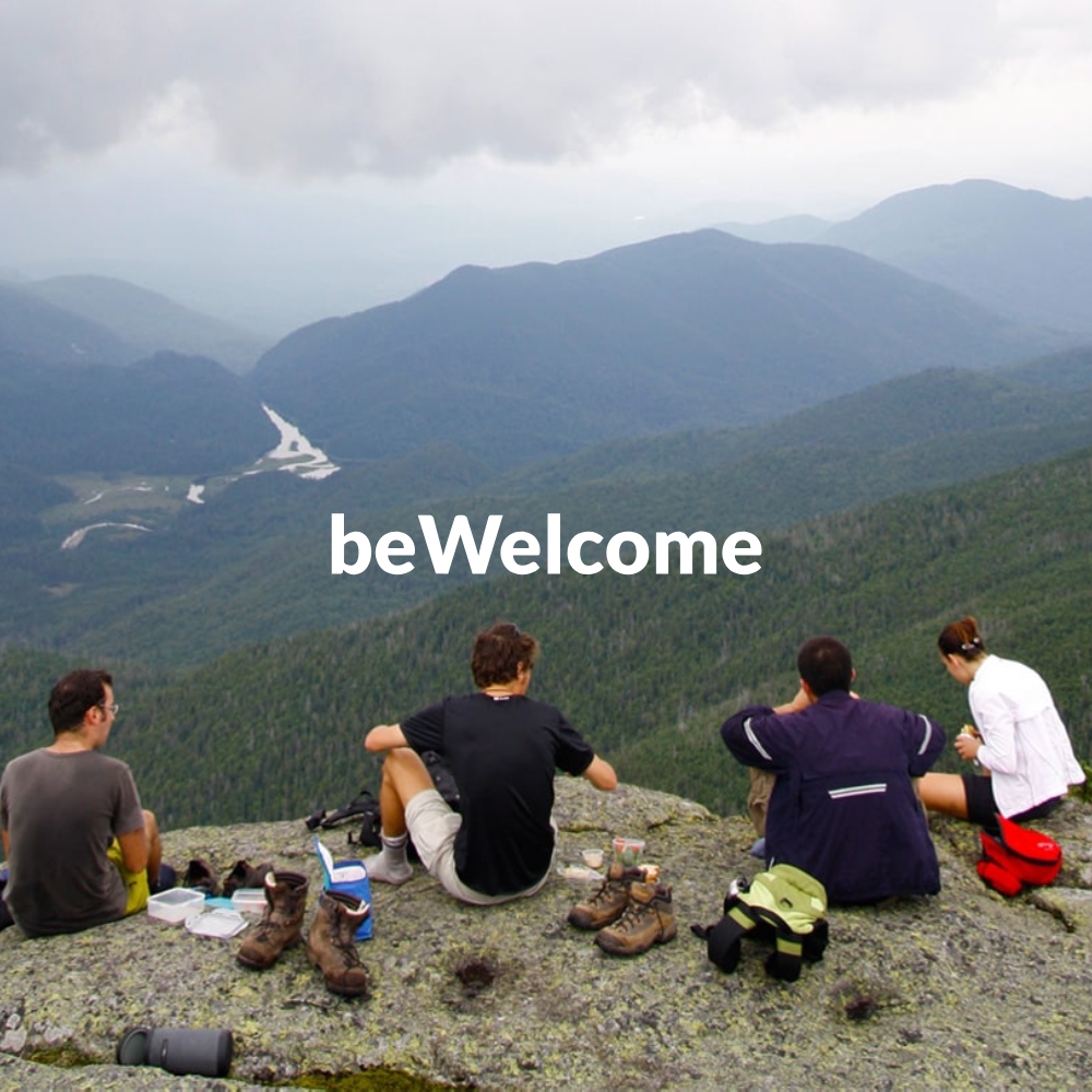 Four travellers overlooking a mountain landscape in a BeWelcome hospitality exchange promotional image