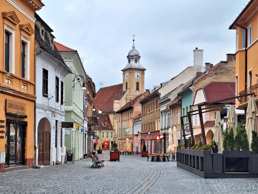brașov street scene Charming Cobbled Street in Brașov Lined with Colourful Buildings and a Clock Tower