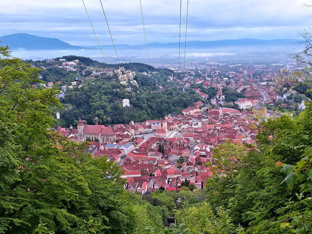 brașov views from tampa hill Aerial View of Brașov’s Red Rooftops and Green Hills from Tâmpa Hill with Cable Lines Overhead