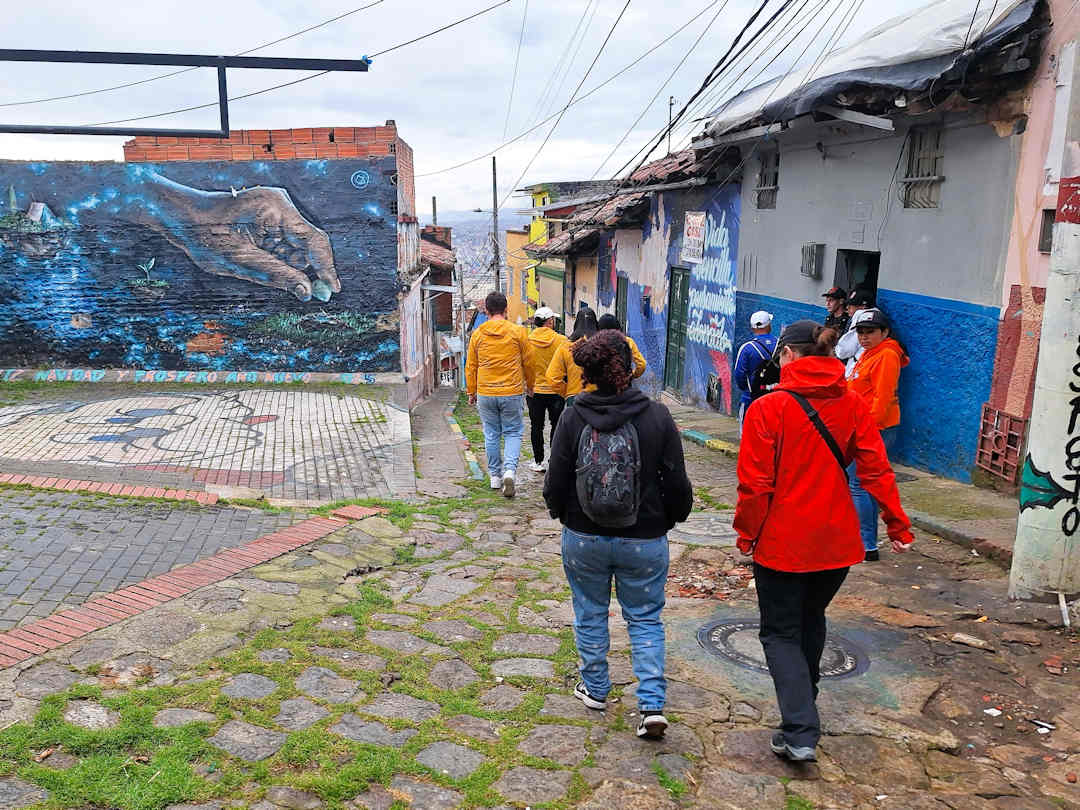 breaking borders tour group in barrio egipto Travellers exploring Barrio Egipto Bogotá with Breaking Borders guides, passing murals that tell the community’s history and transformation