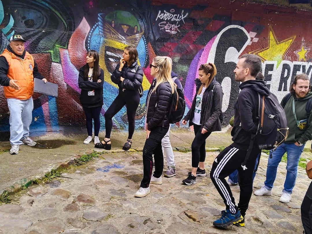 calabazo with breaking borders tour group Breaking Borders guide showing a mural to visitors during the Barrio Egipto Walking Tour in Bogotá