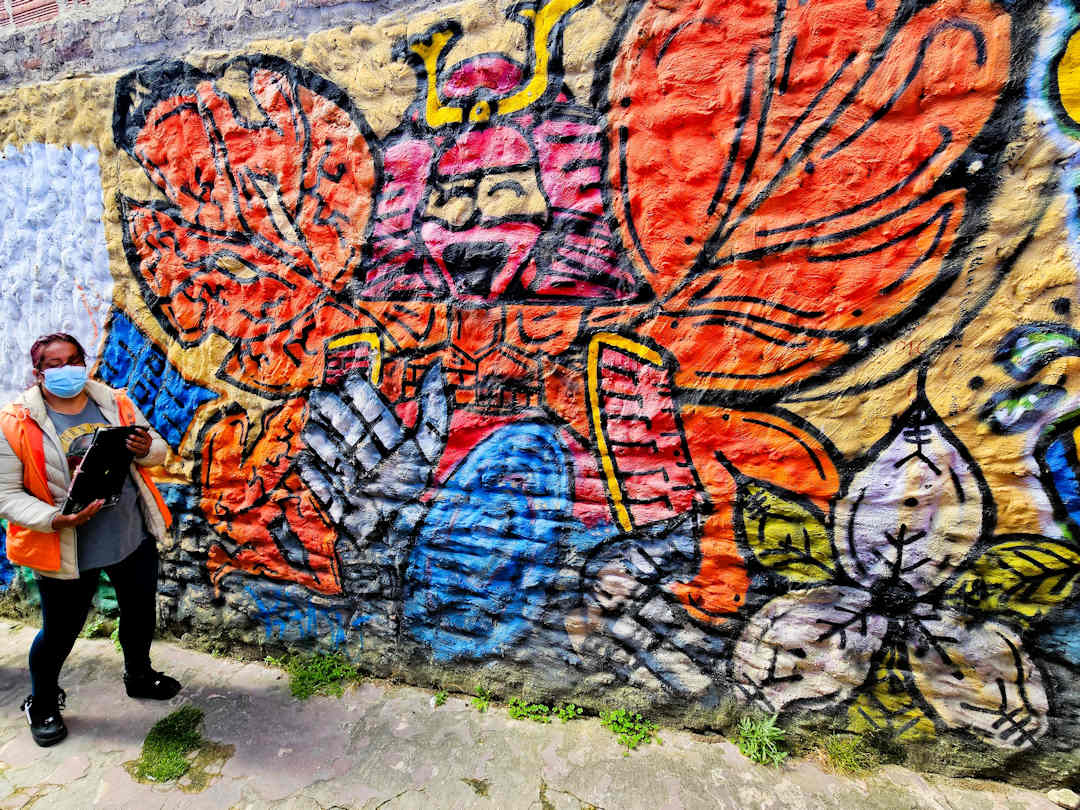 carmen from breaking border explaining butterfly mural Breaking Borders guide in front of the butterfly mural in Barrio Egipto Bogotá, symbolising violence in the past and hope for the future