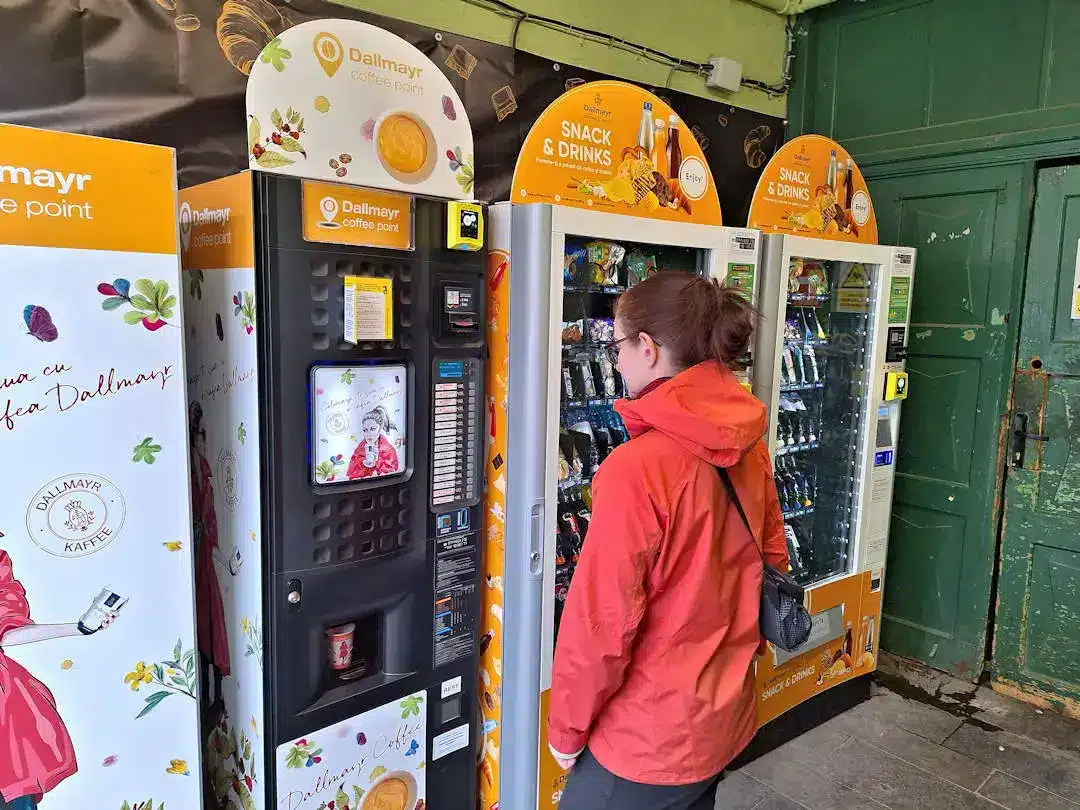 Coffee vending machine in Sibiu Person using vending machines indoors.