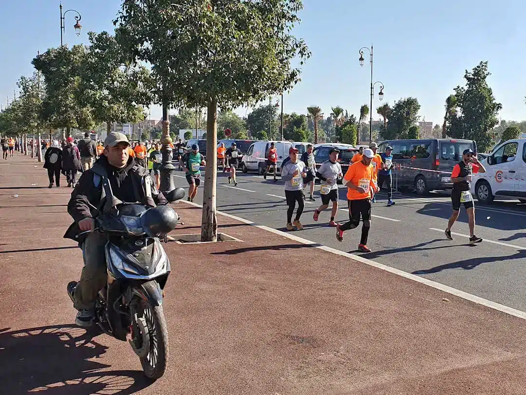 Marathon runners and motorcyclist on sunny city street