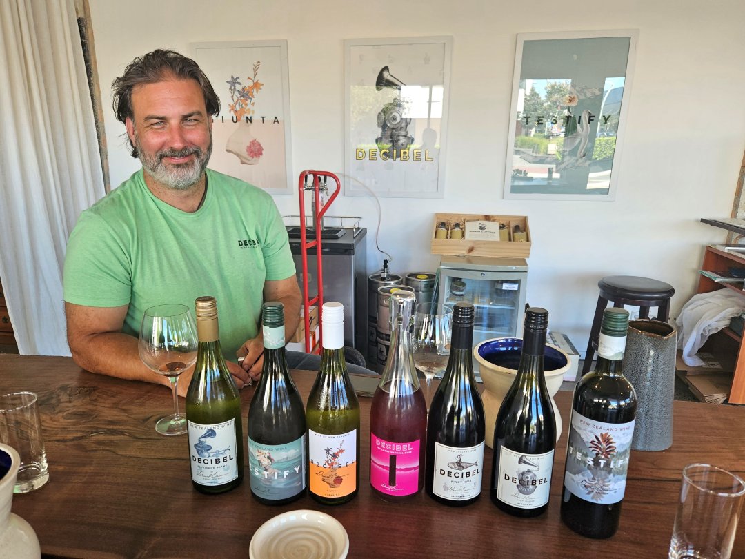 Man seated behind wine bottles at tasting table