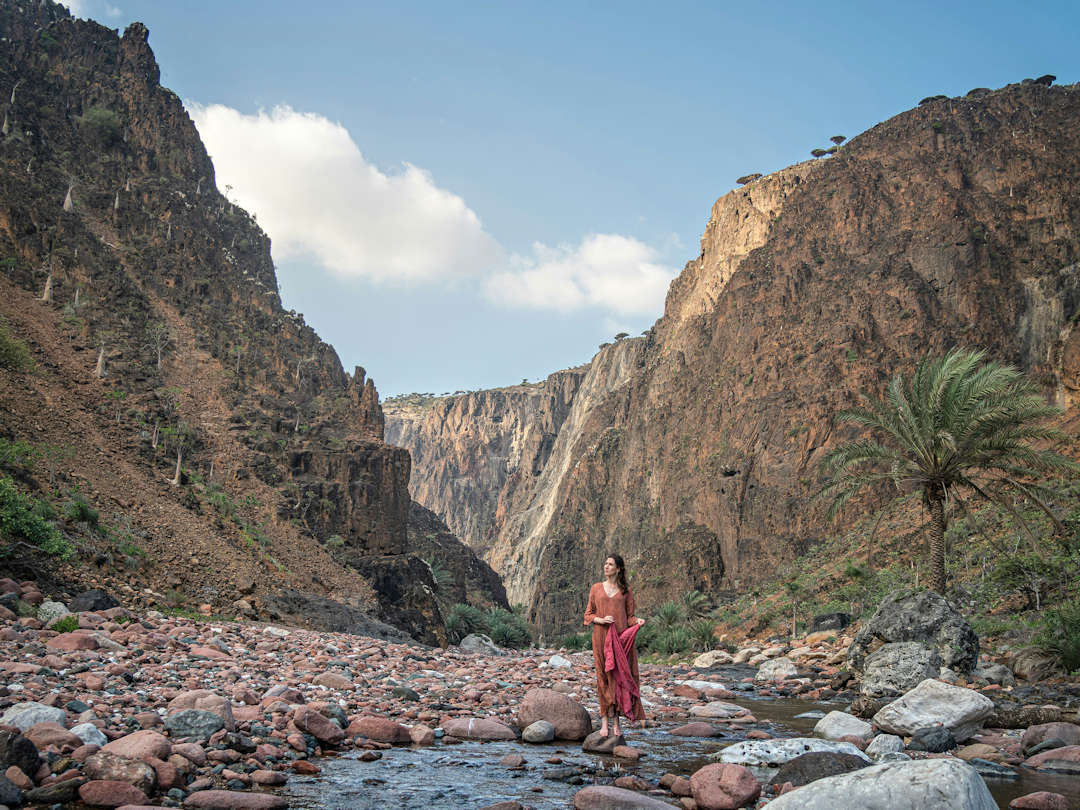 derhur canyon by andrew svk on unsplash Woman stands in rocky desert canyon landscape.