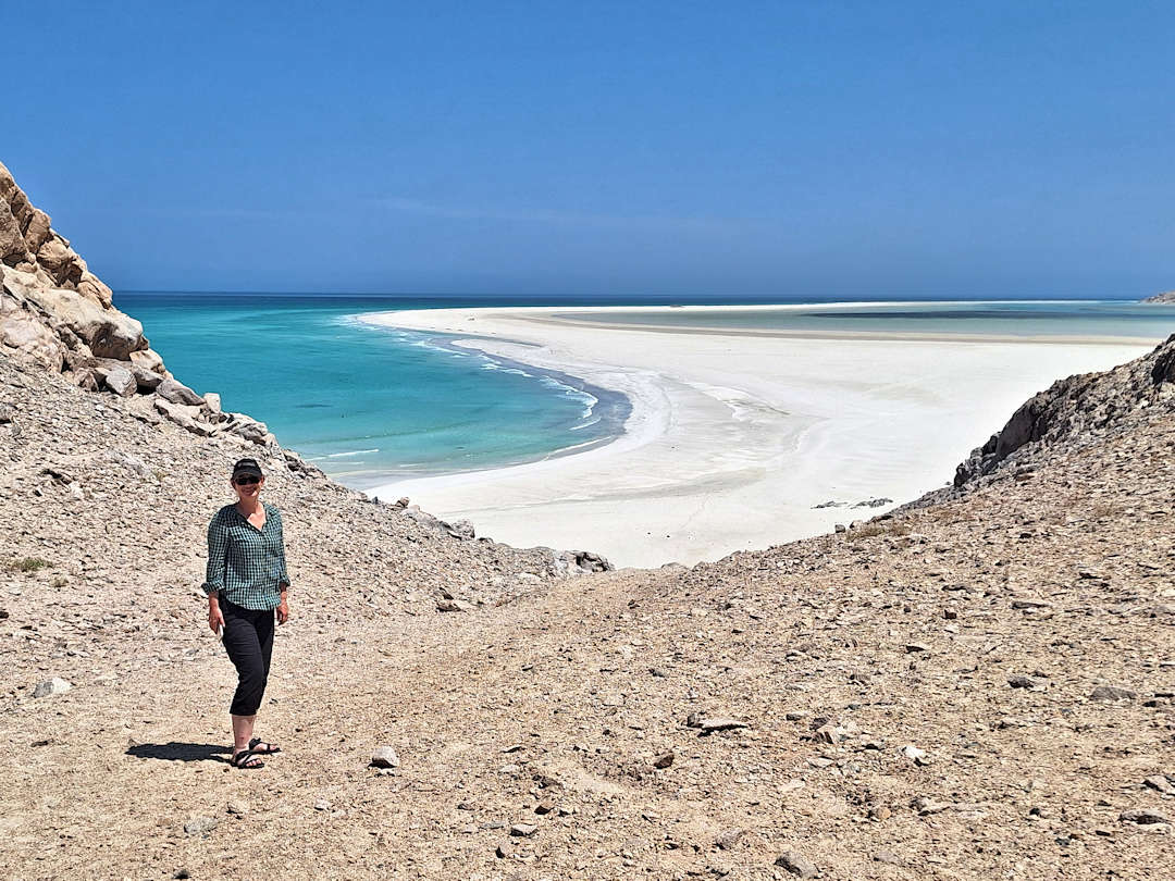 detwah lagoon Person standing by pristine beach and clear blue water.