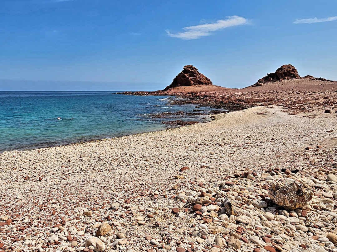 dihamri Rocky beach with blue ocean and clear sky.