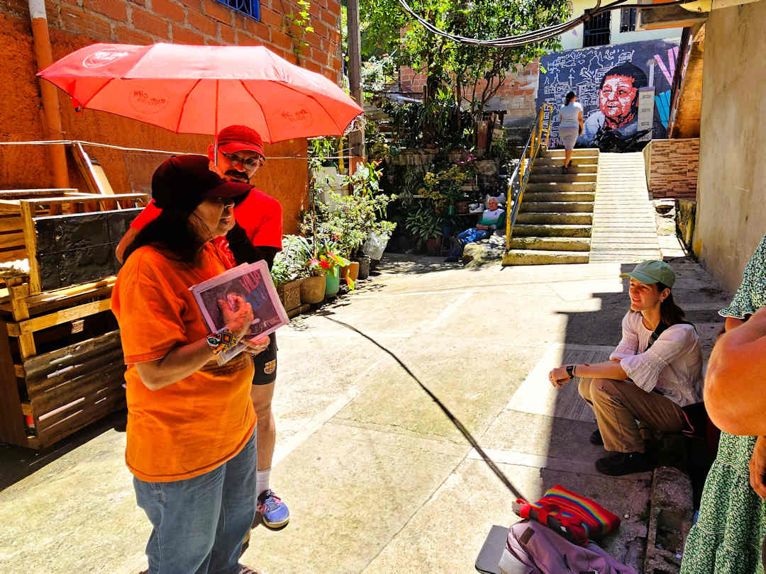 heroína sharing her life story in barrio fidel castro of moravia Community leader in Moravia speaking to visitors with photos during the Comuna 4 Barrio Transformation Tour