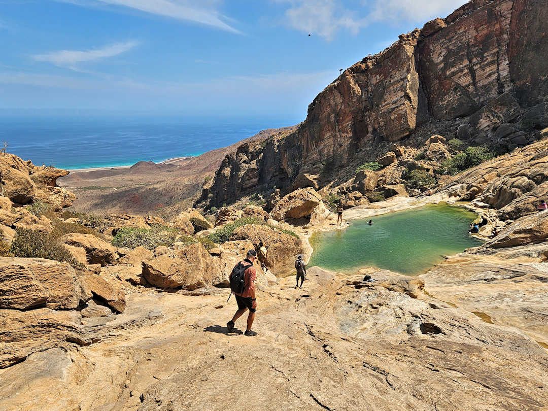 homhil Hikers near desert pool with ocean view