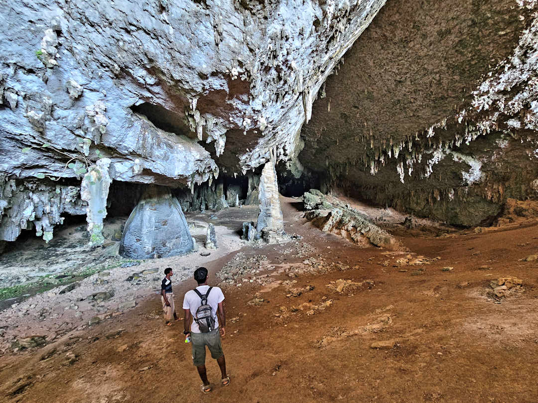 hoq cave People exploring large underground cave with stalactites.