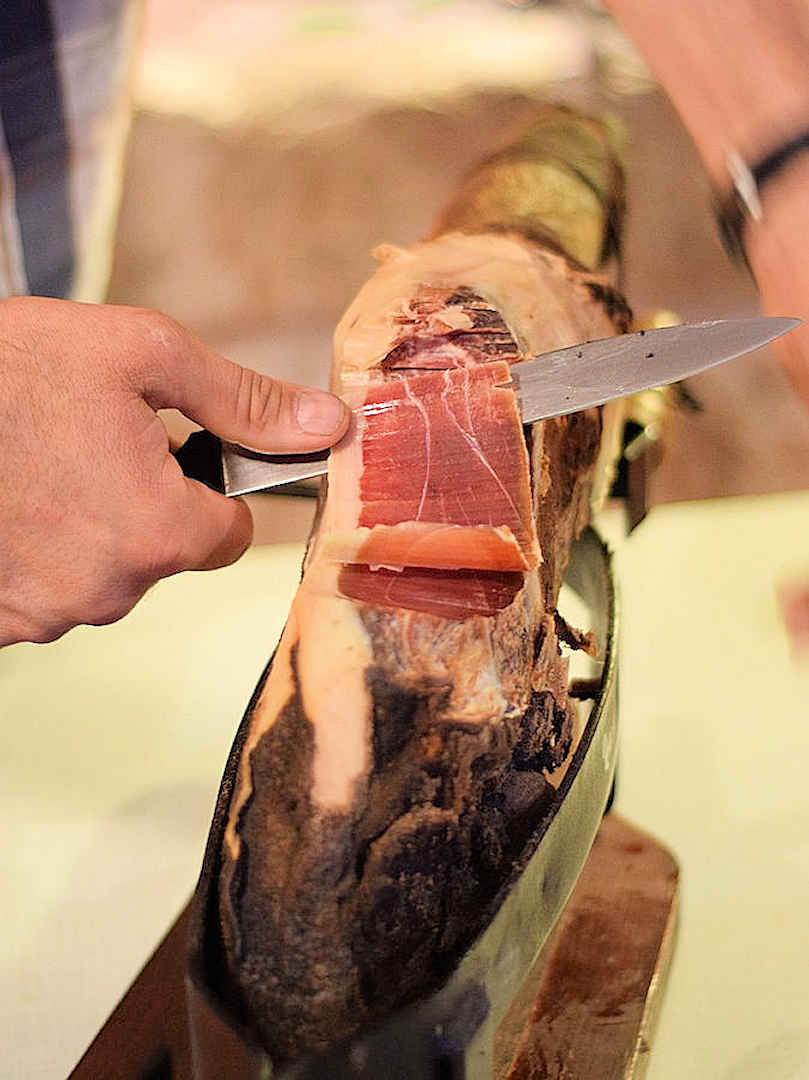 man carving prosciutto by brimfulof on pixabay
