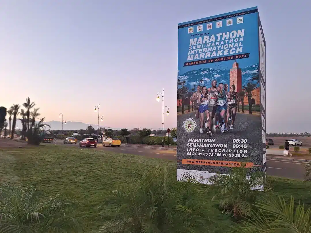 Marrakech marathon billboard by roadside at dusk.