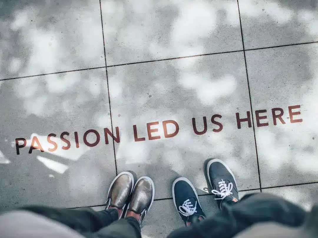 Shadowy feet by 'Passion Led Us Here' sidewalk text.