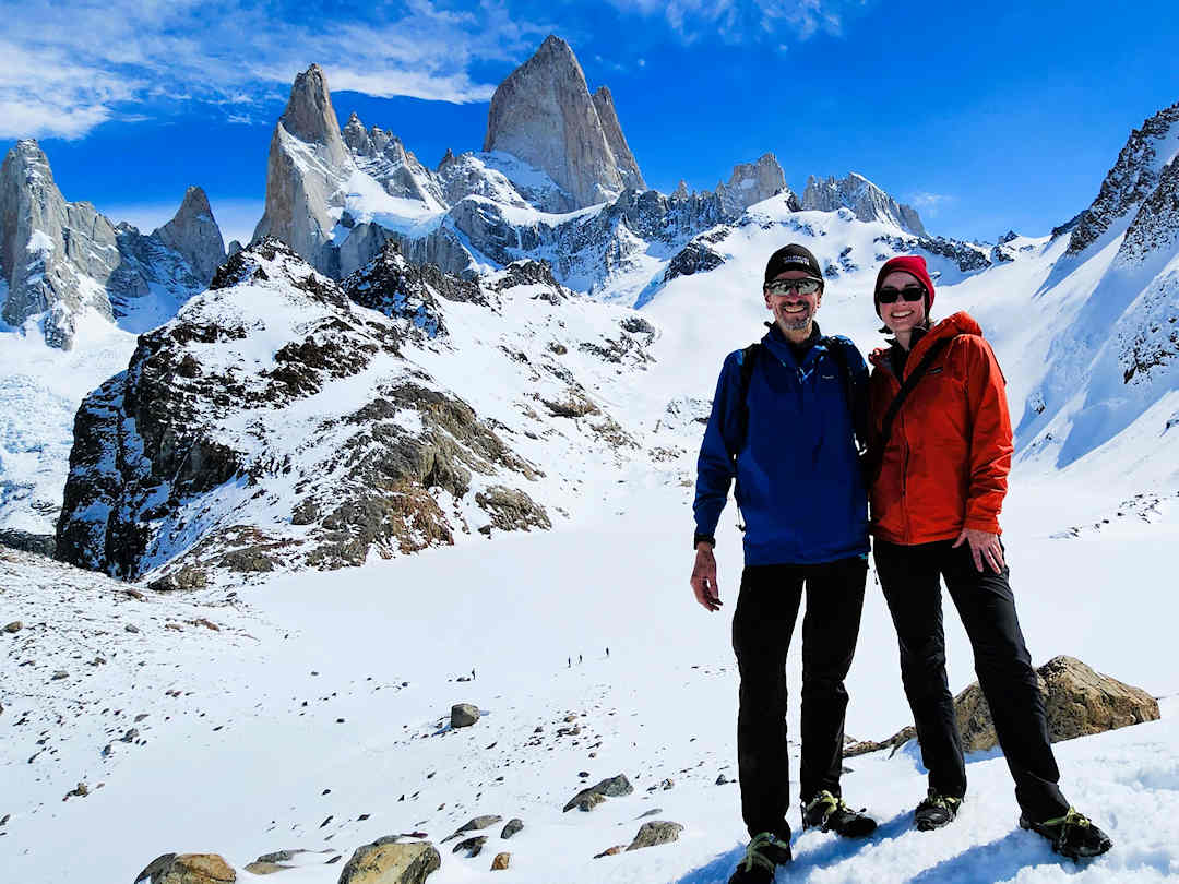 Paul and Sandra standing at the edge of Laguna de los Tres with Mount Fitz Roy massif rising behind them in Los Glaciares National Park, Argentina