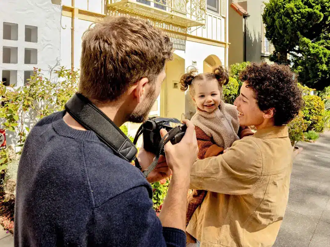Man photographing family with a toddler outdoors.