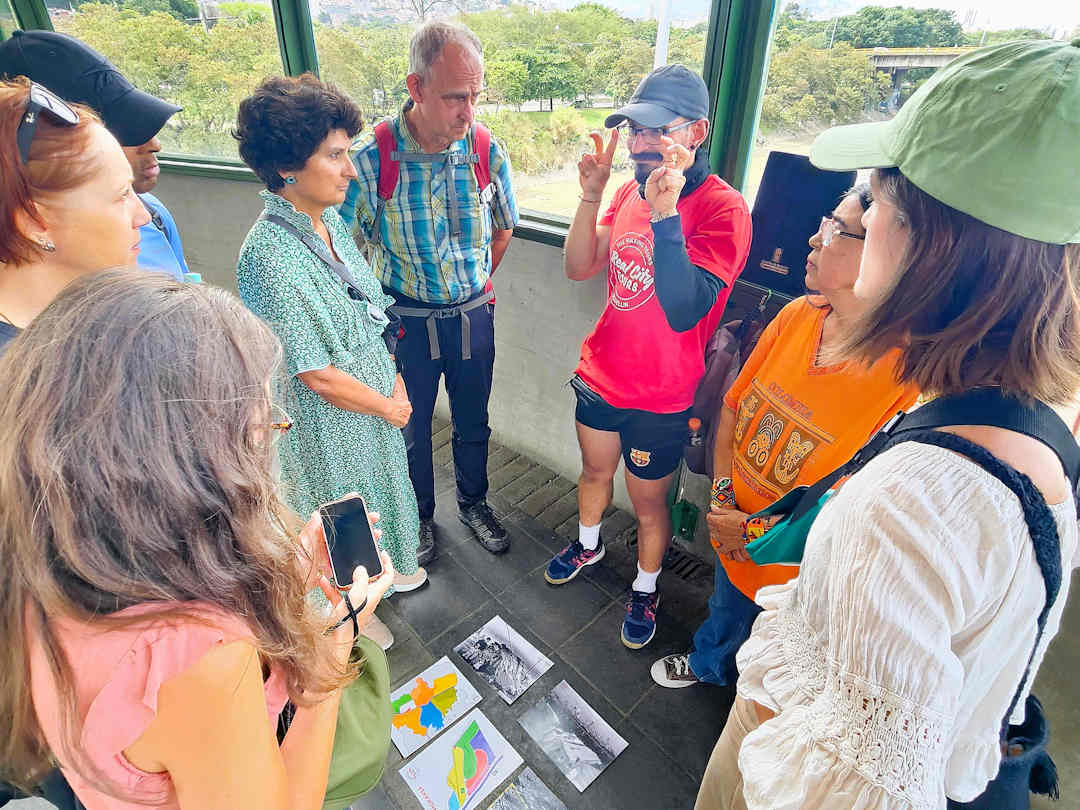 real city tour group at caribe metro station Guide explaining Moravia’s history to visitors with maps and photos during the Comuna 4 walking tour in Medellín