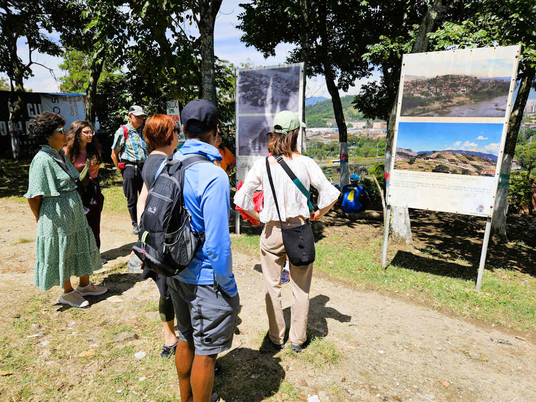 real city tour group on top of el morro Visitors viewing historic photos of Moravia’s rubbish dump and transformation during the Comuna 4 walking tour in Medellín