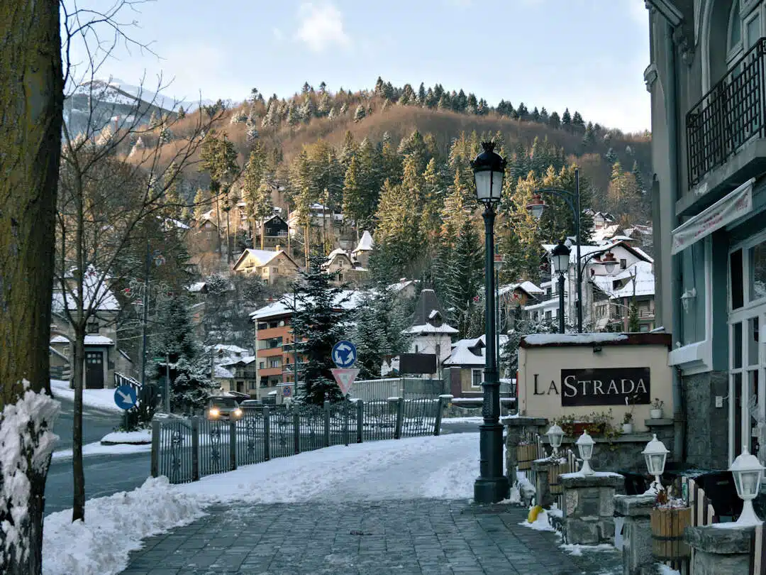 Winter Streetscape in Sinaia Romania with Snow-Covered Hills and Shops