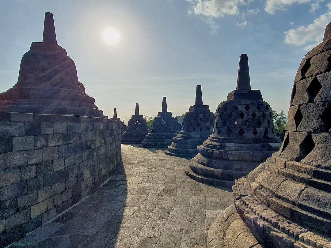 Sun over top stupas at Borobudur