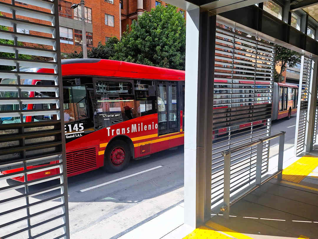 transmilenio bus passing station Red TransMilenio bus at a Bogotá station, part of the city’s public transport system used to reach Barrio Egipto
