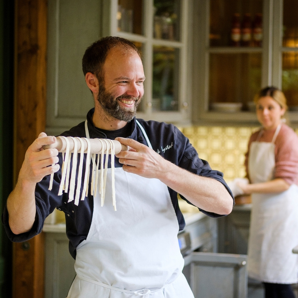 Local cooking class experience booked through Viator, showing travellers learning pasta-making from a regional chef.