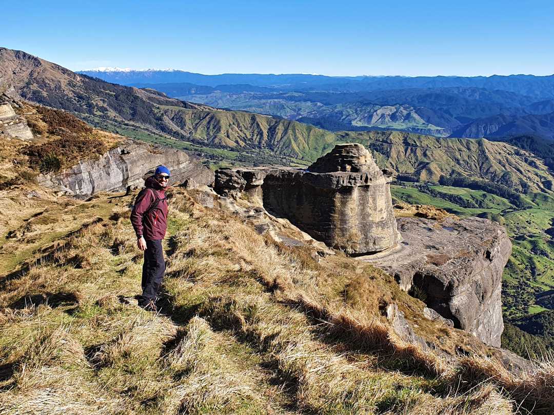 Hiker on cliff overlooking vast mountain valley
