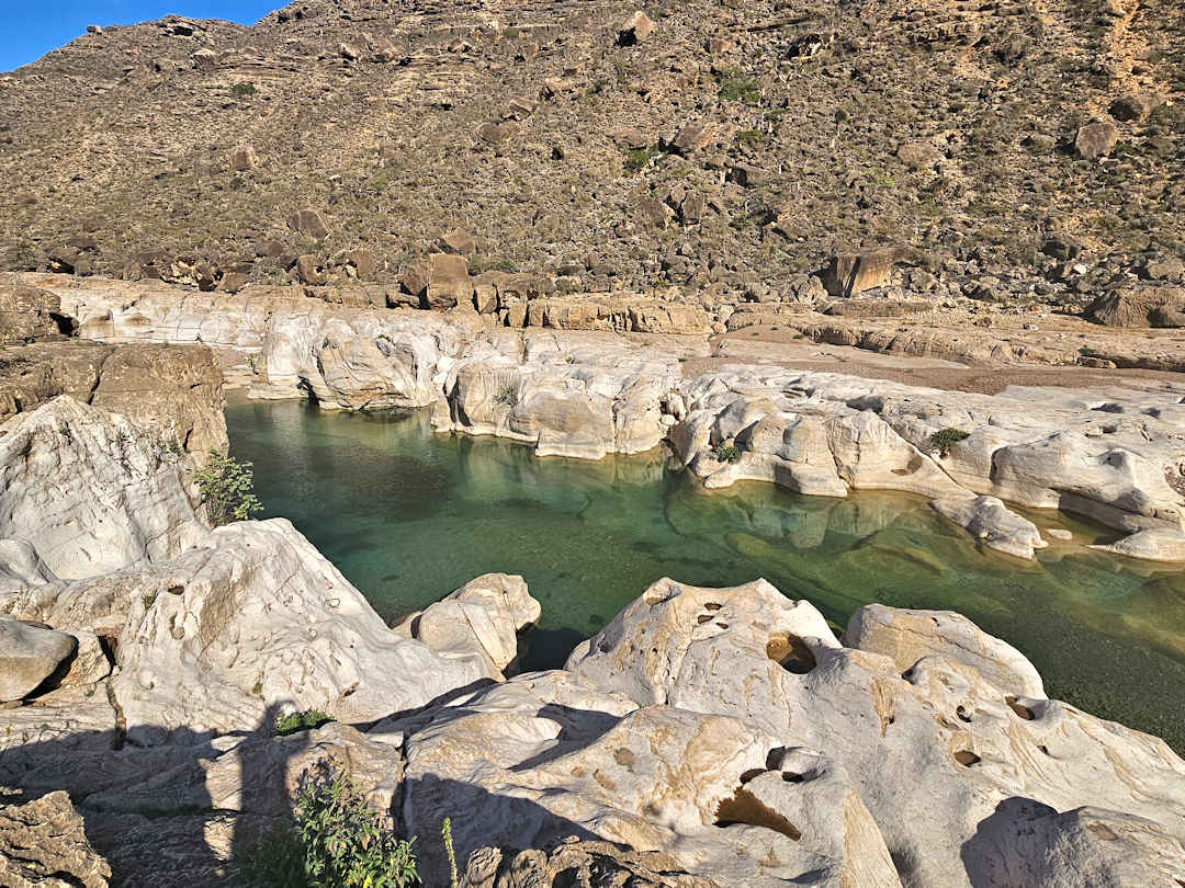 wadi kalisan Rocky desert landscape with small green water pool.