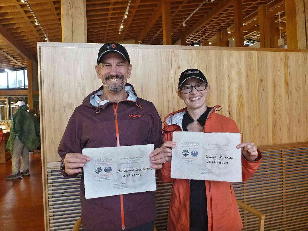 Two pilgrims showing their Dual Pilgrim certificates